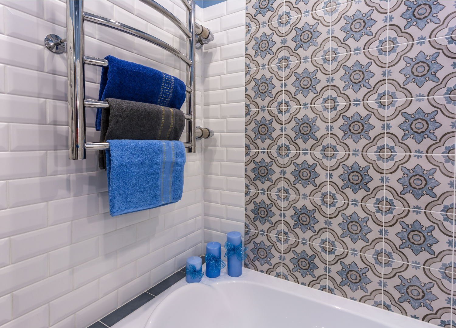 Ett badrum med blått kakel och blå handdukar.