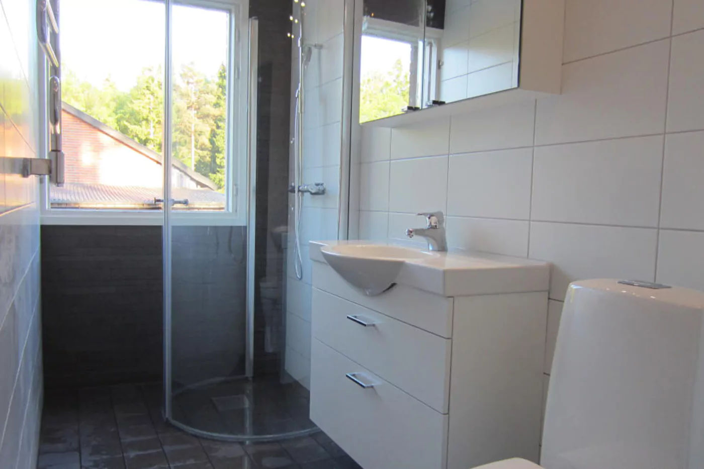 Ett vitt badrum i Uppsala med stora fönster.